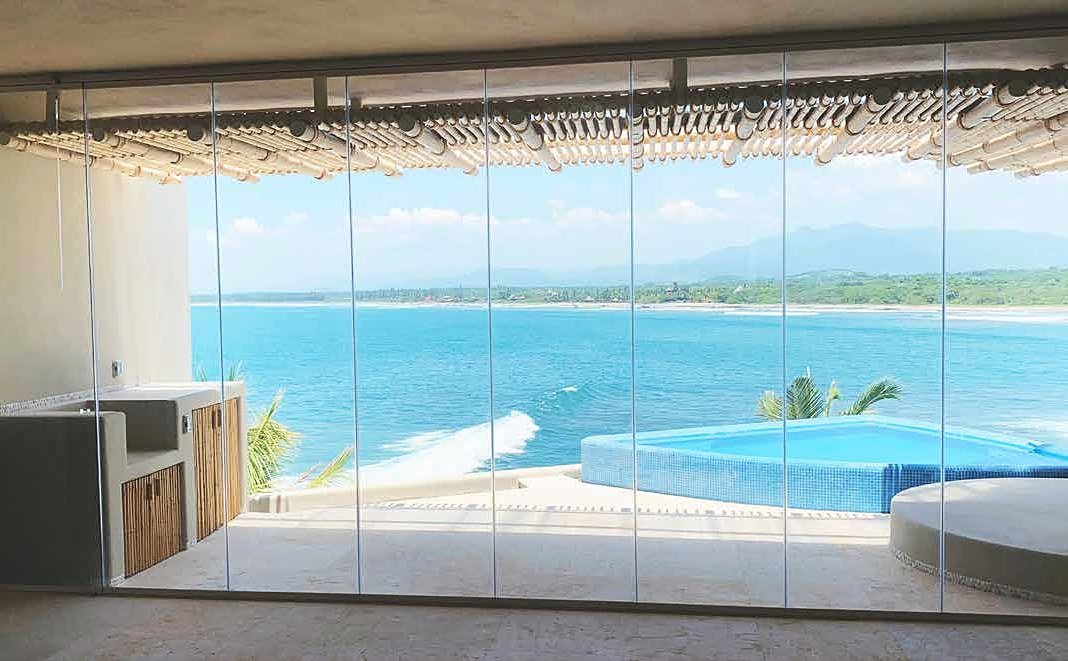Área envidraçada com CLAROFLEX Pivot e vista para o mar